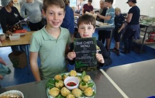 Boys presenting their final meal cooked at school with vegetables grown in their school garden.